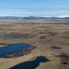 Aerial view of pools and grassland with mountains behind