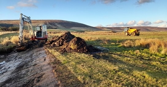 A digger and truck undertaking wetland creation work