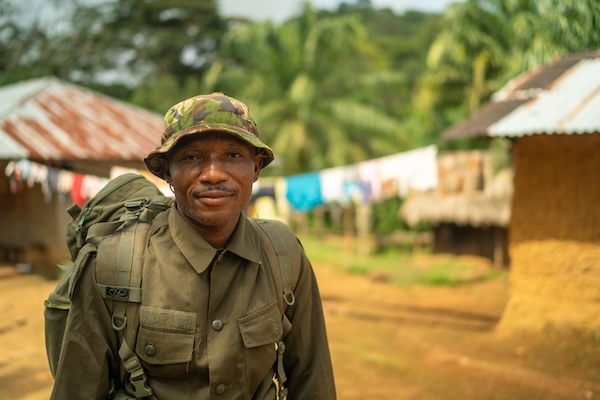 A ranger standing in a village and gazing at the camera