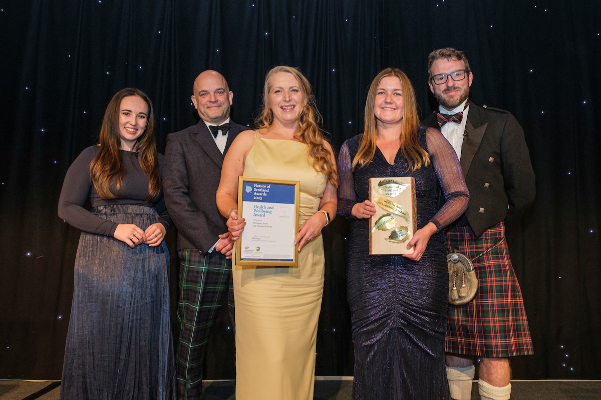 The winners of the 2023 Nature of Scotland Health and Wellbeing Award hold their trophies alongside hosts Megan McCubbin and JJ Dillon.
