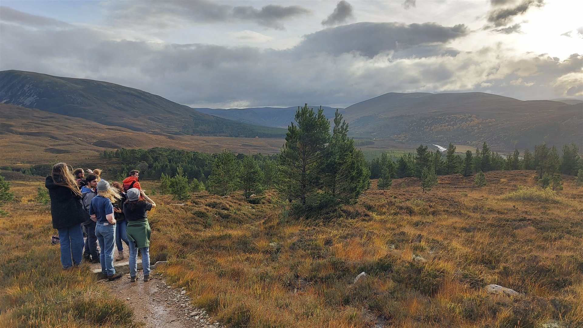 A group of young people looking out over a mountainous landscape.