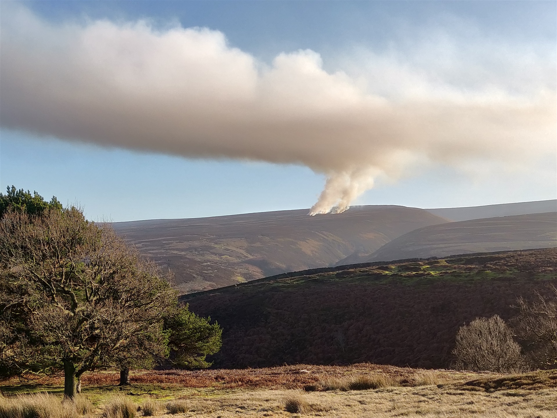 Clouds of smoke above hills.