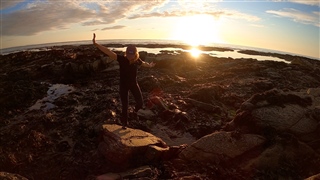 Sophie Pavelle on a rocky beach at sunset