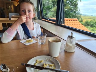 Rhona's daughter sat at a table in the cafe, with the evidence of a very delicious scone!