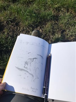 Sketch book with pencils showing a drawing of the salt marsh