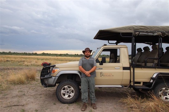 James standing next to jeep on the African savannah.