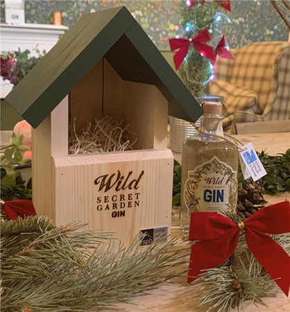 bird box inscribed with 'wild secret herb garden' sits next to wild gin bottle