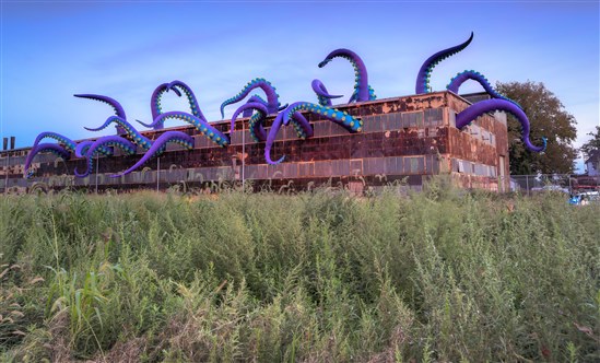 empty building with art installation depicting large purple tentacles coming out of it
