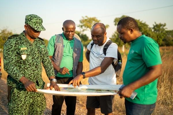 Four people study a map out in the field