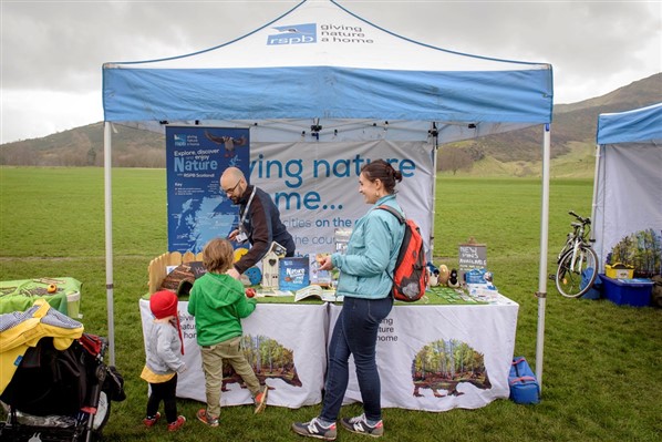 a family speaking to a staff member at an RSPB tent