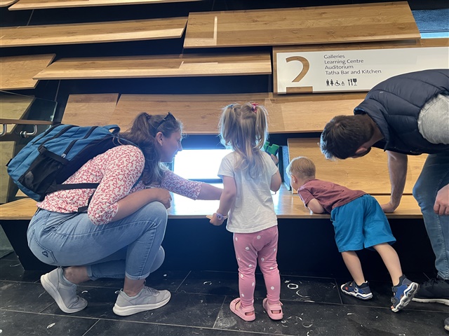 Two adults and two children are looking at an information panel is Dundee's V&A museum.