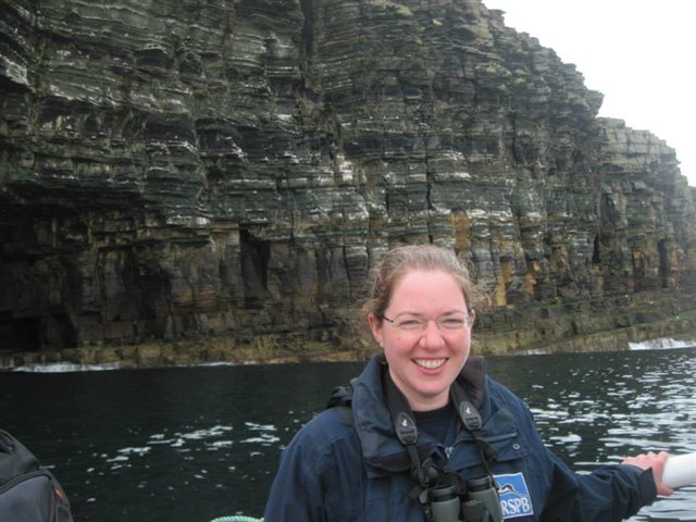 Lorna on a boat in front of impressive seabird cliffs