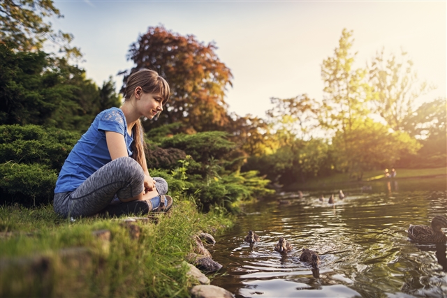Young person sitting beside lake watching wildlife