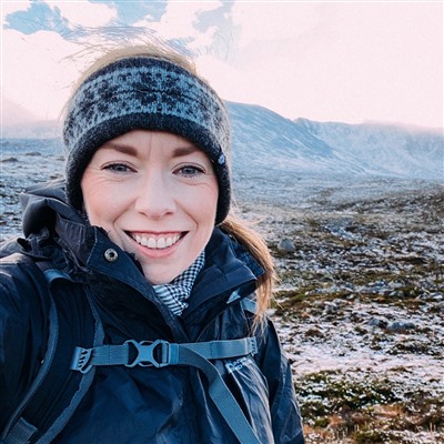 Kate on a snowy mountain, wrapped up warm and smiling at the camera.